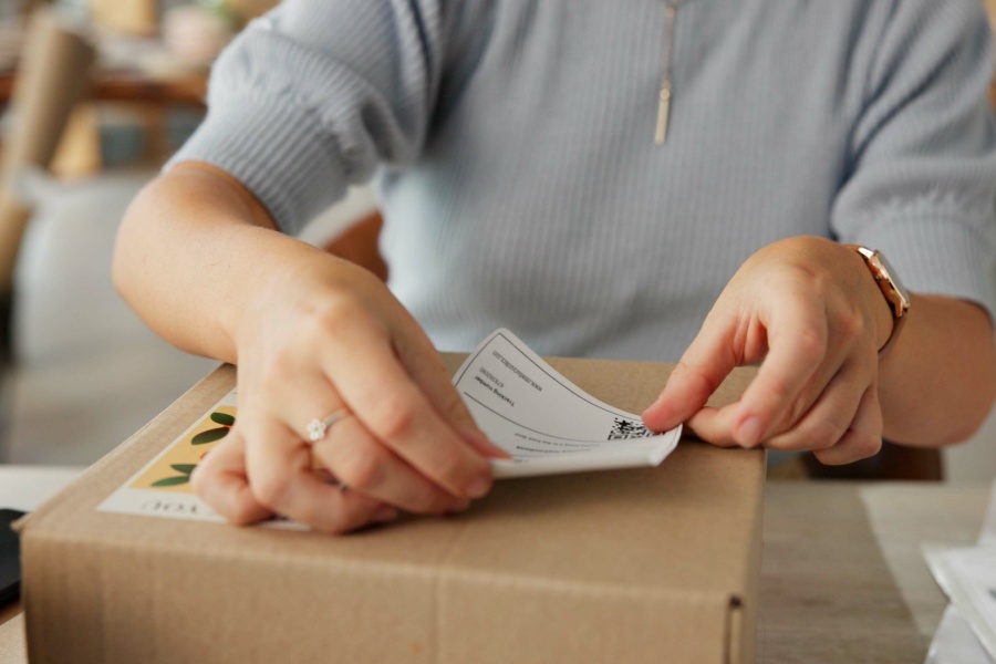 Person putting a shipping label on the box of an e-commerce order